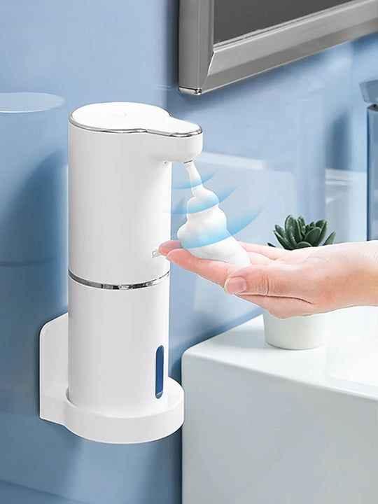White automatic soap dispenser dispensing foam soap into a hand in a modern bathroom