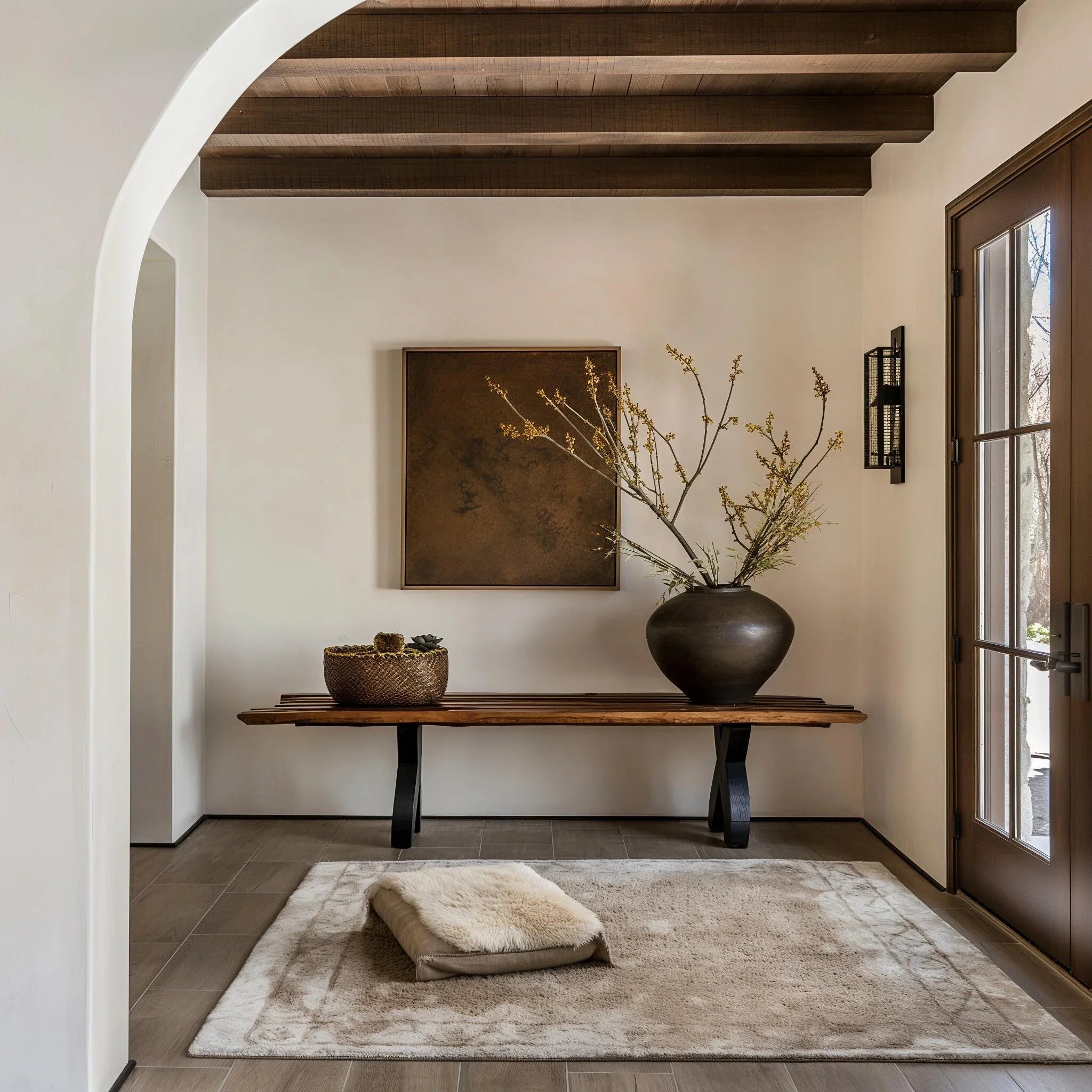 Modern entryway with rustic wood bench, large ceramic vase with branches, and neutral decor