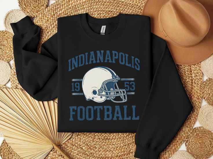 Black sweatshirt with Indianapolis football graphic and vintage helmet, styled with woven mats and a tan hat