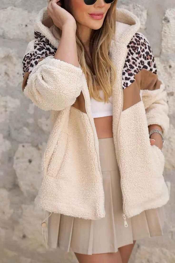 Woman wearing cream sherpa fleece jacket with leopard print and brown accents, beige pleated skirt, and sunglasses