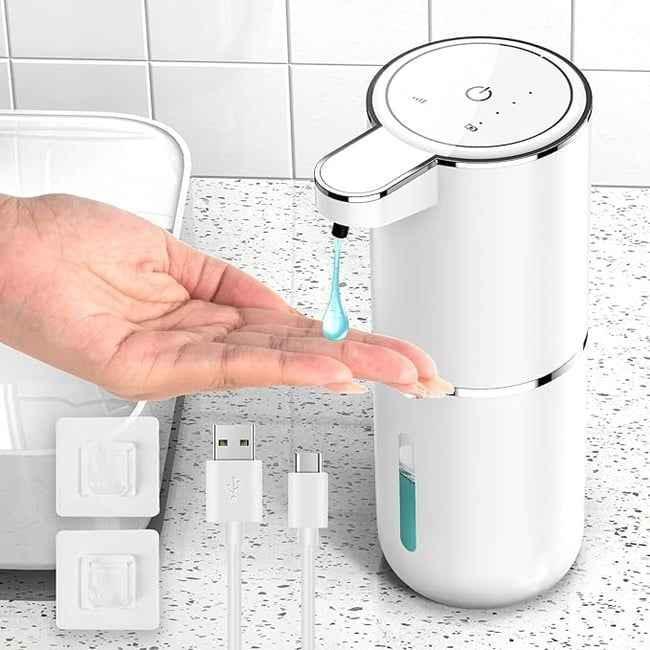 Automatic white soap dispenser dispensing blue liquid soap onto hand on countertop with USB charging cable