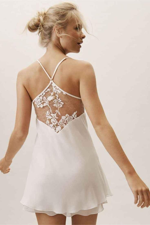 Blonde woman wearing white slip dress with floral lace back detail and spaghetti straps