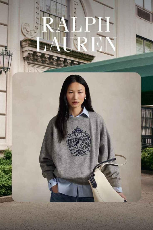 Ralph Lauren ad featuring woman in gray Polo sweater and blue shirt carrying white handbag in urban setting