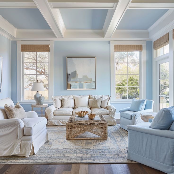 Living room with light blue walls, white furniture, and large windows.