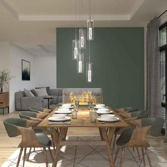 Modern dining room with wooden table set for eight, green accent wall, unique fireplace, and pendant lighting