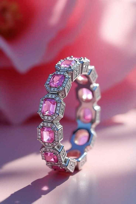 Silver ring with multiple pink square gemstones surrounded by small diamonds on pink background