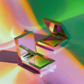 Open square eyeshadow compacts with green shimmer on colorful reflective background