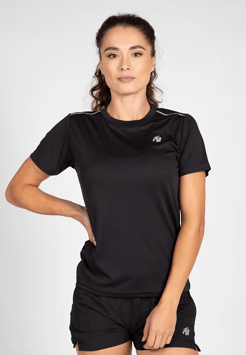 Woman wearing black athletic t-shirt and shorts with logo, posing against white background
