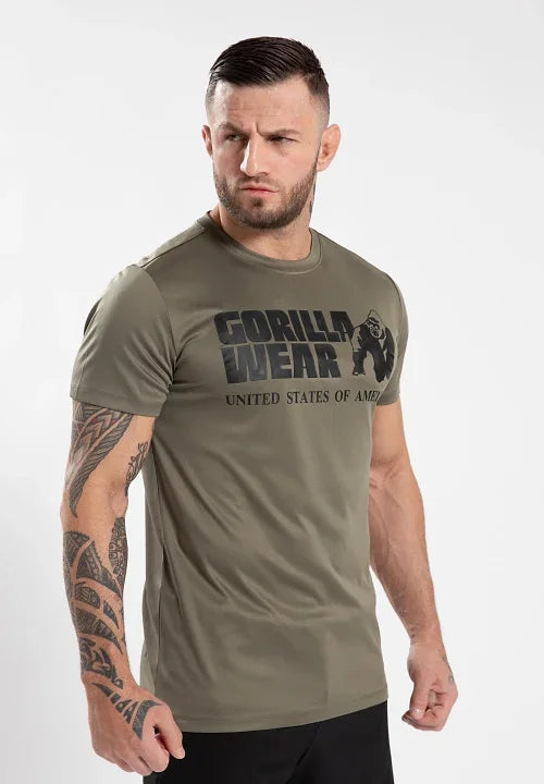 Muscular man with tribal arm tattoo wearing olive green Gorilla Wear T-shirt against white background